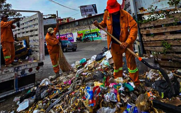 Trabajadores de aseo urbano suben llantas y colchones viejos a un camión de volteo municipal en Cuernavaca, Morelos