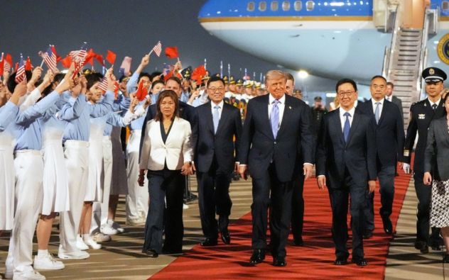 El presidente Donald Trump en la ceremonia de bienvenida en el aeropuerto de Pekín, flanqueado por su comitiva oficial.