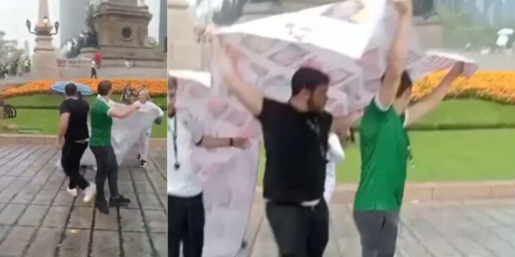 Aficionados aglomerados bajo la lluvia junto a las escalinatas del Ángel de la Independencia en la Ciudad de México