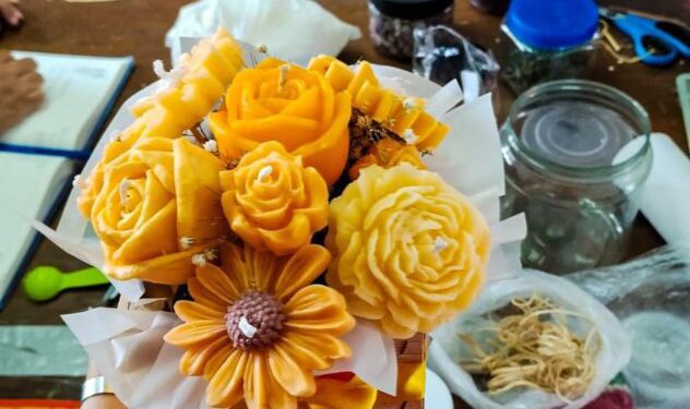 Mujeres elaborando velas aromáticas artesanales con moldes y fragancias en un taller comunitario de Cuernavaca, Morelos